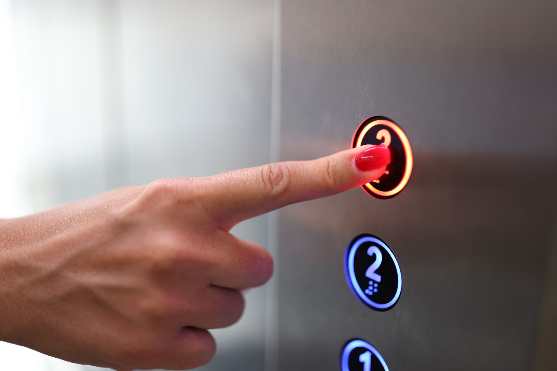 Woman finger presses a button in elevator closeup